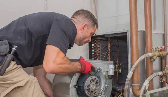 HVAC technician repairing a residential heating system motor in a utility area
